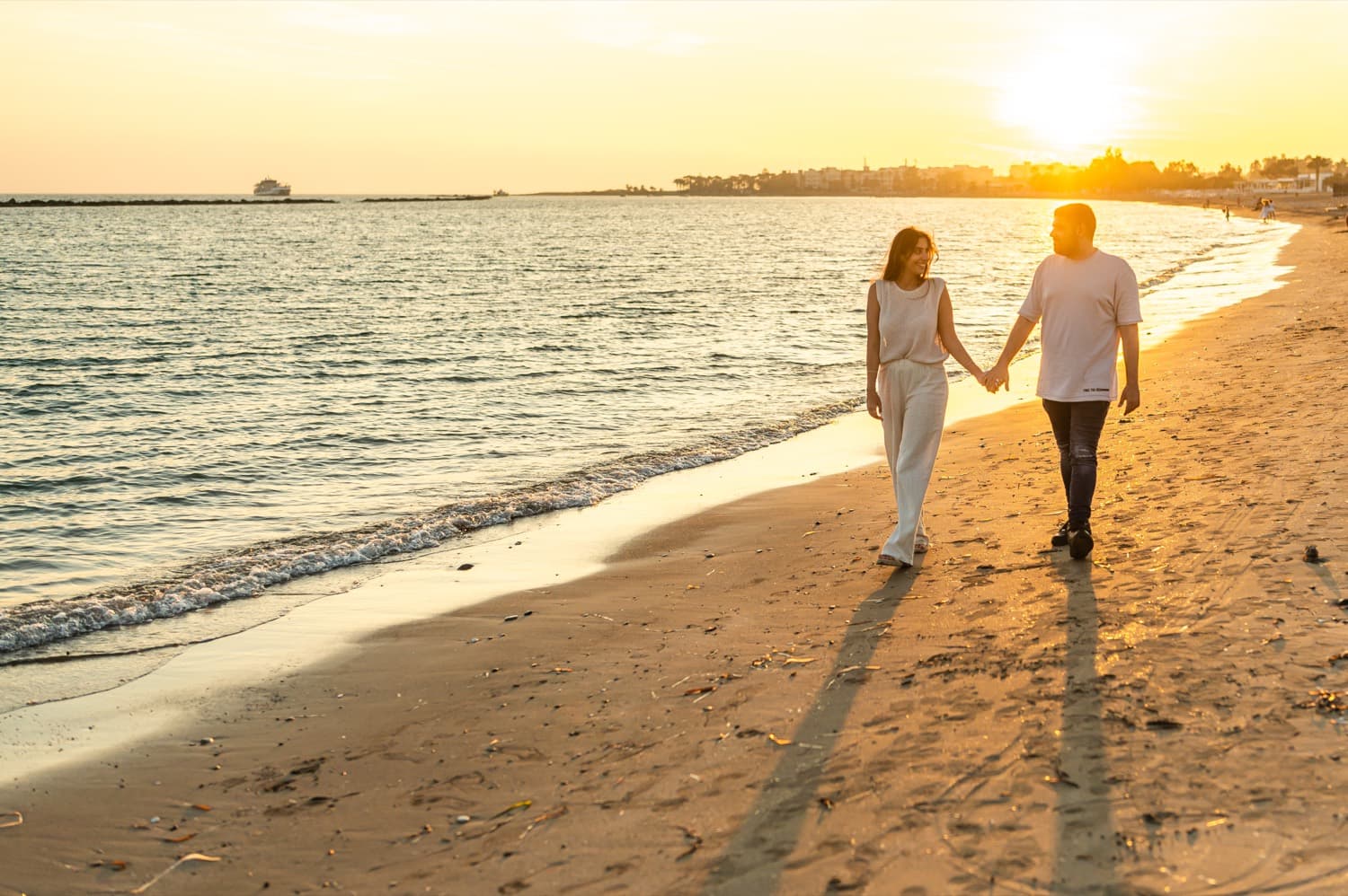A couple walking hand in hand along a golden sunset beach in Cyprus